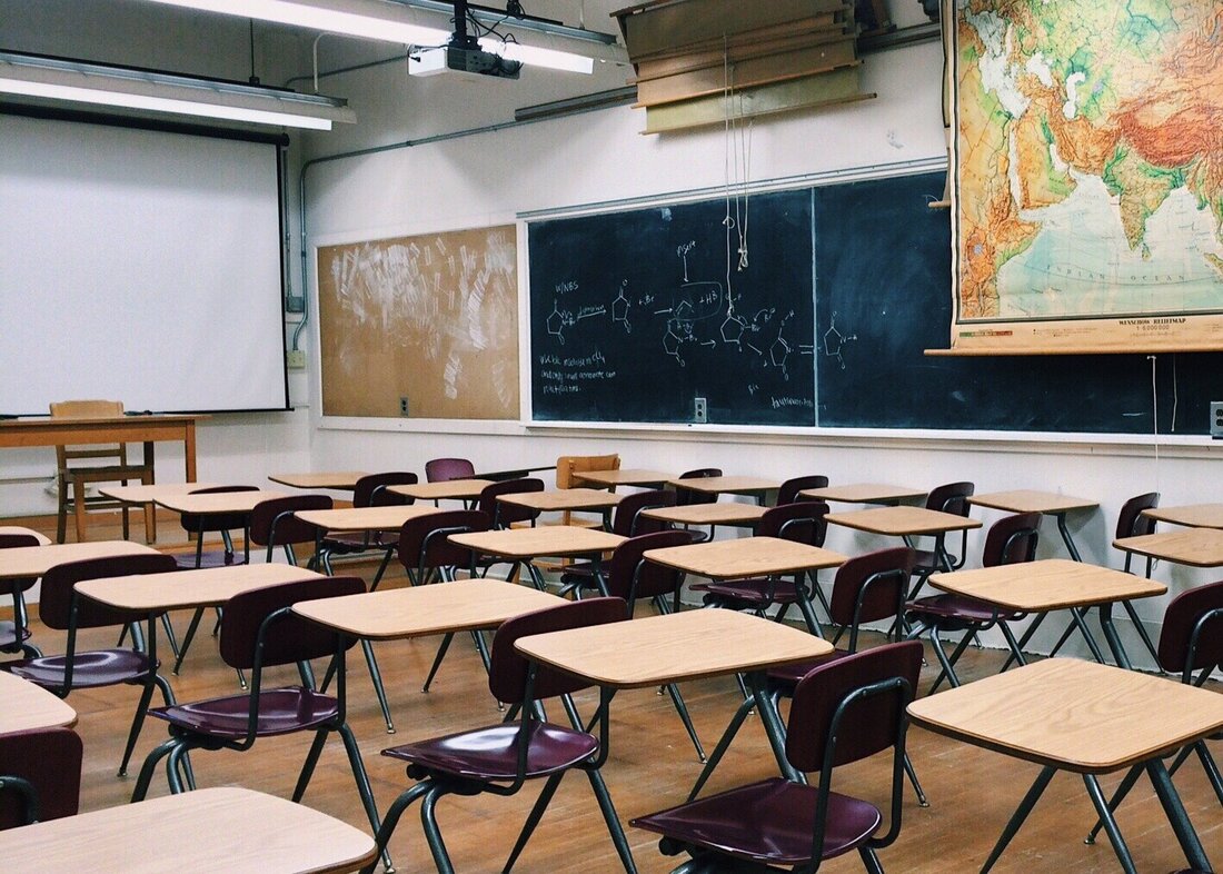 Classroom with desks, chalkboard, and map