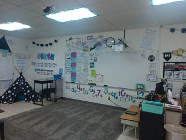 Empty classroom with rug, whiteboard, low tables, and mountain decor
